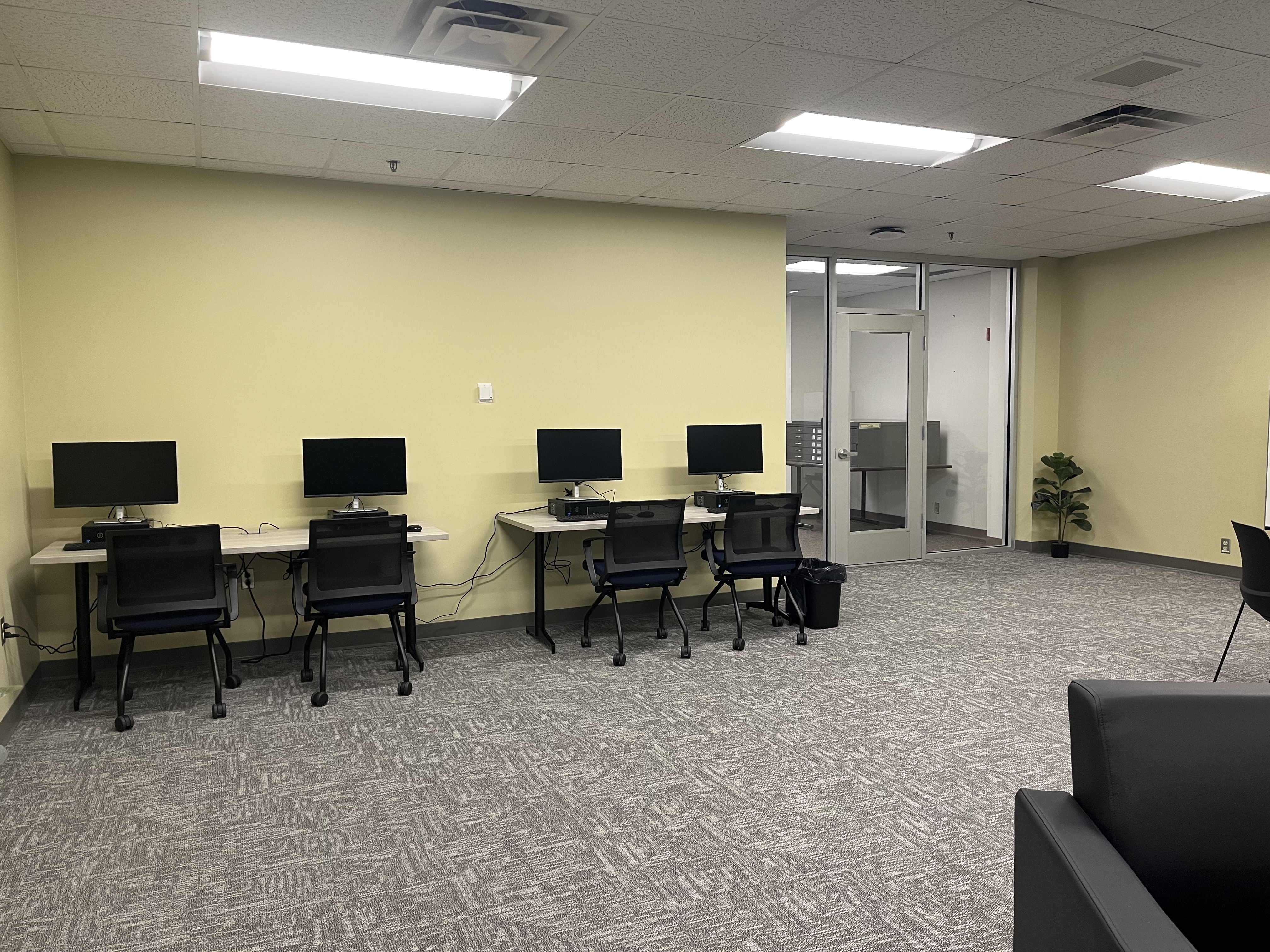 A picture of 4 computer systems next to each other on a table with their respective chairs